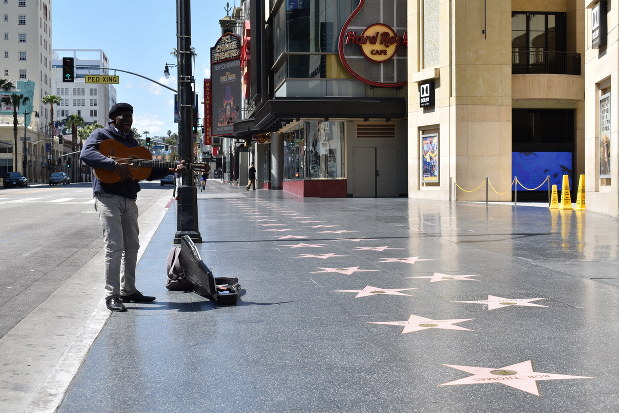 ほぼ無人になったハリウッド中心部の「ウオーク・オブ・フェーム(名声の歩道)」で路上ライブをする男性ミュージシャン=米西部カリフォルニア州ロサンゼルスで2020年3月26日、福永方人撮影