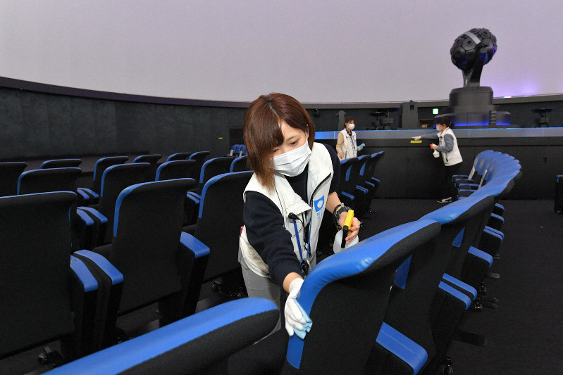 プラネタリウムで座席や手すりなどを消毒するスタッフたち。投映回数を半減させて、合間を消毒作業に充てている=福岡市中央区の市科学館で2020年3月28日、森園道子撮影