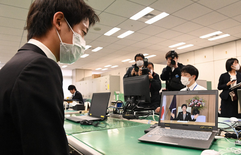新型コロナウイルス感染拡大防止のため、パソコンの動画で小池百合子知事のメッセージを聞く東京都の新入職員(左)=都庁で2020年4月1日午前11時4分、大西岳彦撮影