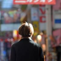 かつて母親に深夜連れ回された大阪・梅田の繁華街を見つめる北川幸（仮名）。「どこに行くんやろ、いつ帰るんやろ、早く帰りたいなって、我慢していました」＝大阪市北区で2020年3月6日、平川義之撮影