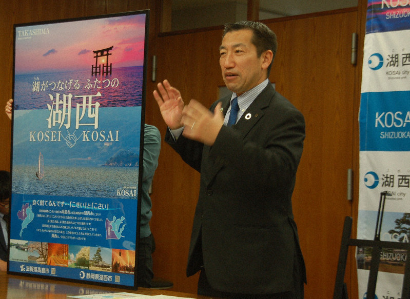 琵琶湖西岸の湖西地方にある滋賀県高島市と共同製作した「湖西」ポスターを発表する湖西市の影山剛士市長=滋賀県湖西市役所で