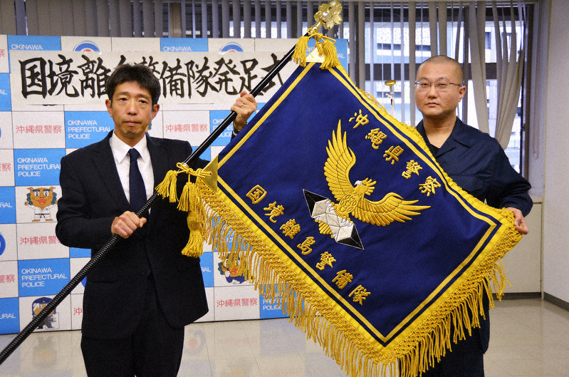 沖縄県警に国境離島警備隊が1日新設され、隊旗を授与された小林雅哉隊長(右)=那覇市の県警本部で1日、竹内望撮影