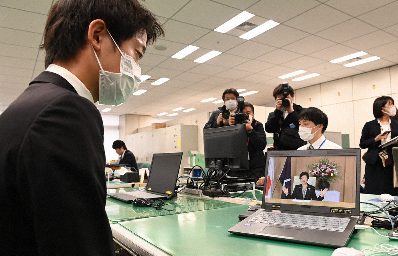 新型コロナウイルス感染拡大防止のため、パソコンの動画で小池百合子知事のメッセージを聞く東京都の新入職員(左)=都庁で1日、大西岳彦撮影