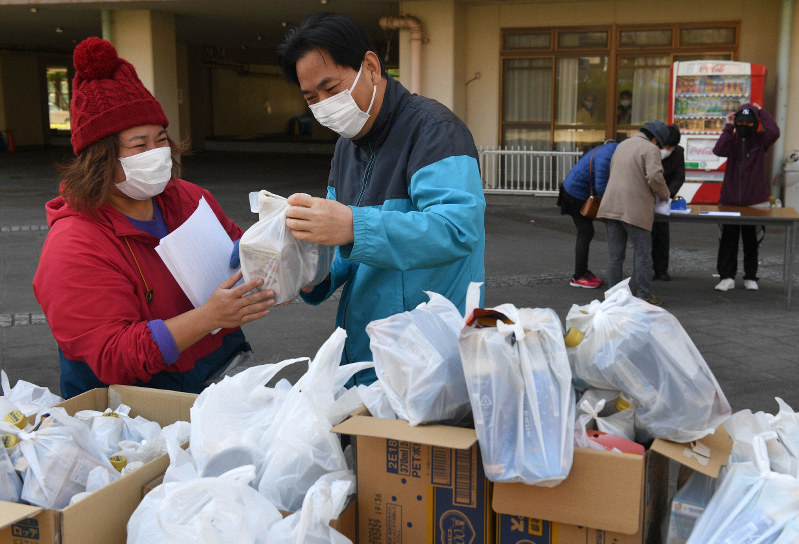 新型コロナウイルスの影響についてのアンケートに答え、食料品などを受け取る外国人住民ら=名古屋市港区の九番団地で2020年4月5日、兵藤公治撮影