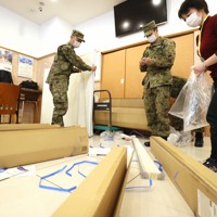 無症状や軽症の新型コロナウイルス感染者を受け入れるホテルのロビーで仕切りを組み立てる自衛隊員ら＝東京都中央区で2020年4月7日午前10時26分、佐々木順一撮影
