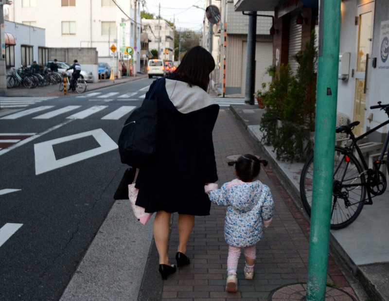 住宅街にある保育園から娘を連れて帰る女性=東京都大田区で2020年4月7日午後5時53分、李英浩撮影