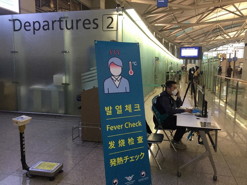 韓国・仁川空港で、出国者が発熱していないかをチェックする職員=2020年3月6日、坂口裕彦撮影