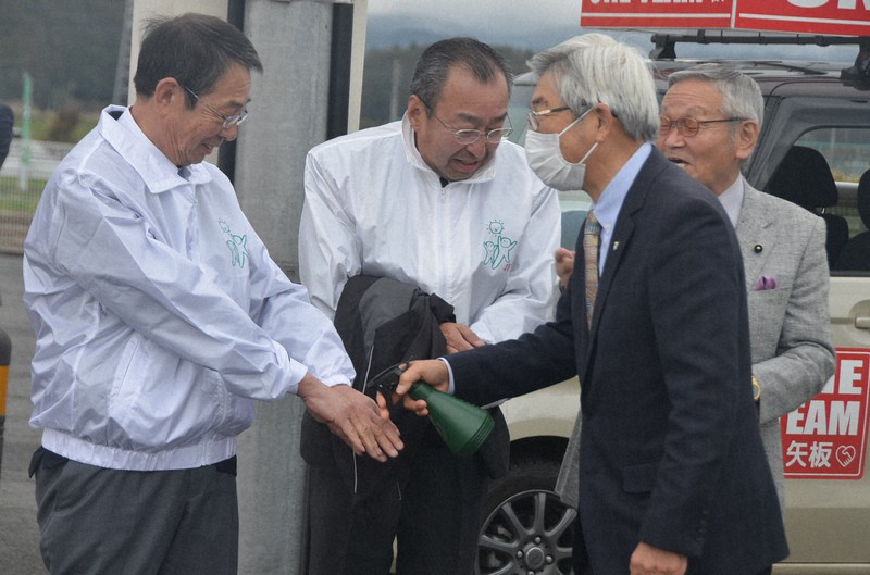 栃木県矢板市長選で、候補者の応援に駆けつけた支持者らにアルコール消毒液をかける陣営関係者=2020年4月5日午前11時15分、湯浅聖一撮影
