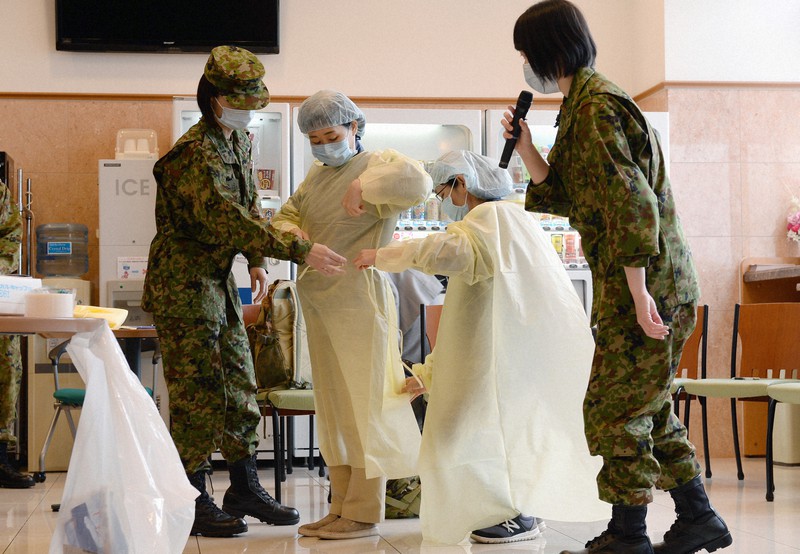 軽症者らを受け入れるホテルで自衛隊の看護官(両端)の指導を受け、防護服の着脱訓練をする研修の参加者=北九州市小倉南区で2020年4月10日午後3時14分、金澤稔撮影