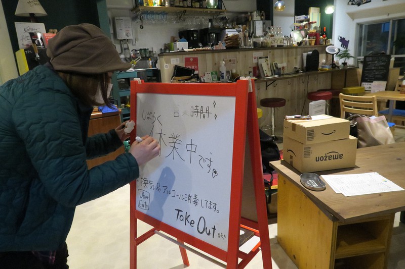 経営する新宿2丁目の店の看板を「休業中」と書き直す長村さと子さん=東京都新宿区で2020年4月3日午後8時29分、藤沢美由紀撮影