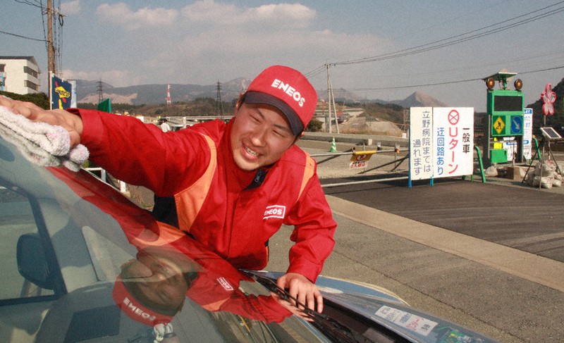 ガソリンを入れに来た車のフロントガラスを笑顔で磨く丸野さん