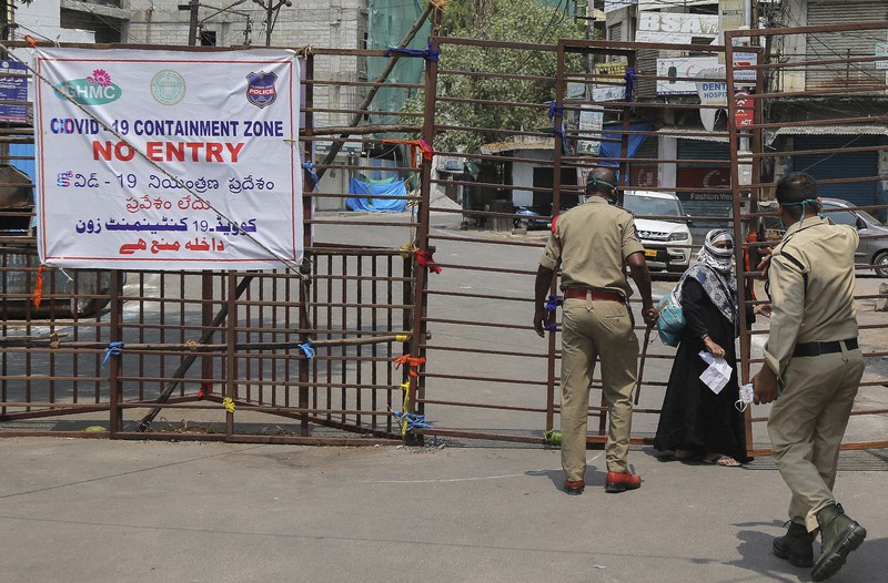 汚染地域に入ろうとする女性を制止する警察官=インド南部ハイデラバードで14日、AP