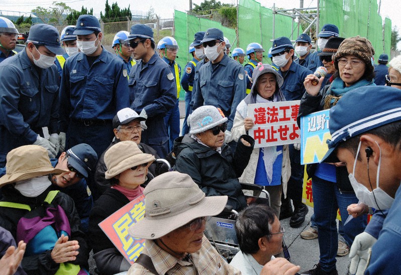 辺野古移設工事の中止を求めて、米軍キャンプ・シュワブのゲート前で座り込む市民と立ち退かせようとする沖縄県警機動隊員=沖縄県名護市で2019年12月27日