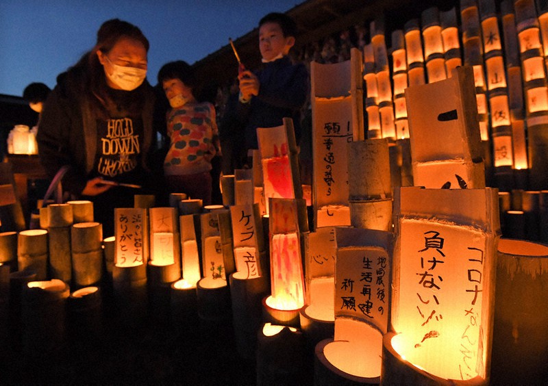 熊本地震から4年を迎え、火がともされた竹灯籠。「コロナなんぞに負けないゾ!」の願いが書かれた灯籠もあった=熊本県益城町の木山仮設団地で2020年4月14日午後7時11分、徳野仁子撮影
