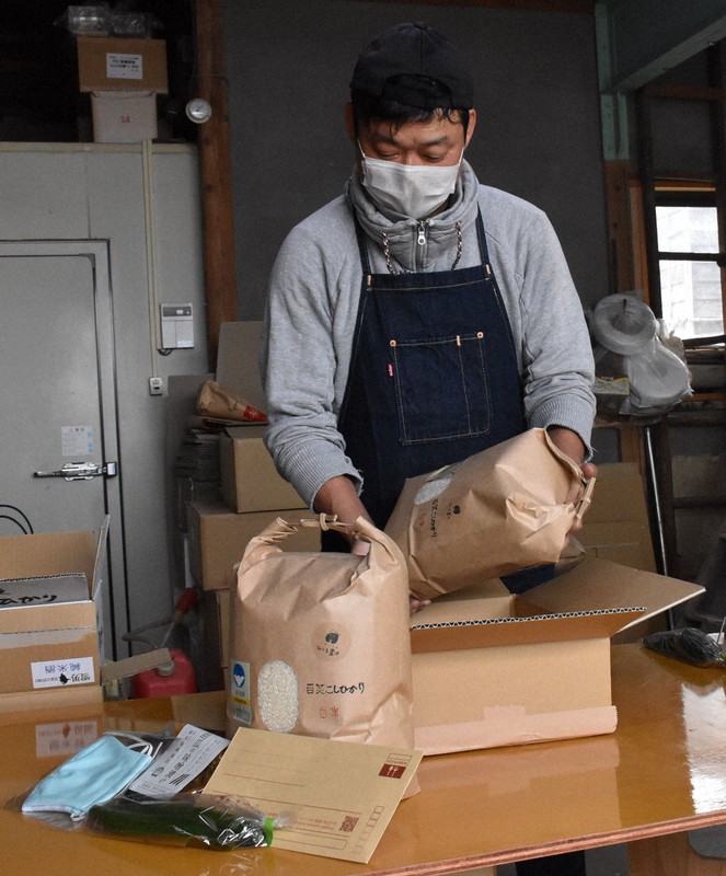 コシヒカリ、きゅうり、マスクなどを荷造りする農家の男性=燕市吉田本町の農場で2020年4月13日午後2時10分、池田真由香撮影