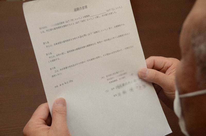 勤務先のロイヤルリムジンのグループ会社と交わした「退職合意書」を見つめる男性=東京都内で14日(画像の一部を加工しています)