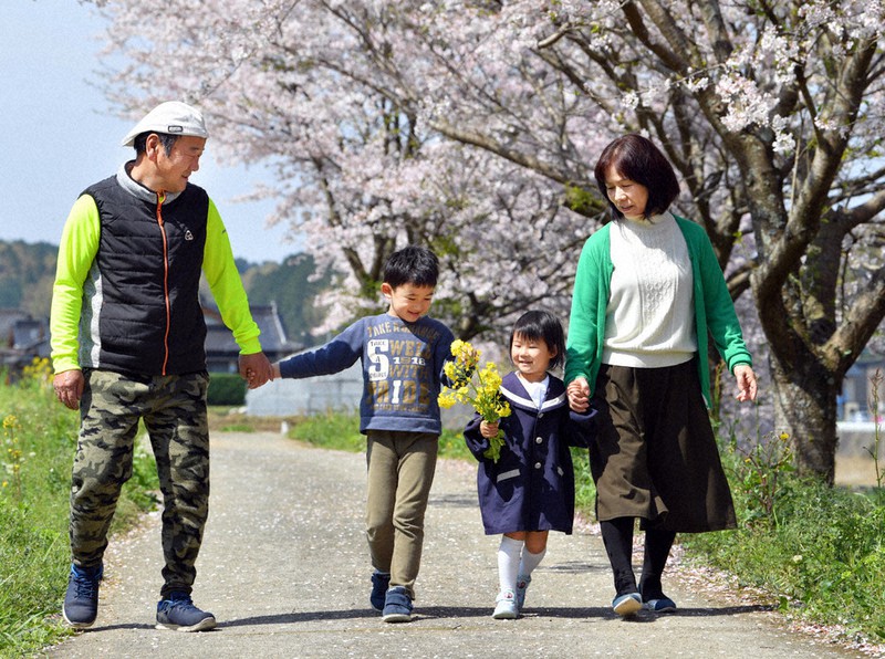 自宅近くの桜並木の下を散策する(右から)祖母の園田久美代さん、のぞみちゃん、兄晟太郎ちゃん、祖父幸治さん=熊本県西原村で2020年4月4日、森園道子撮影