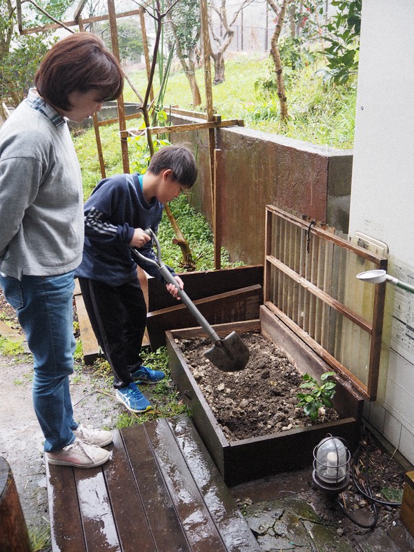 生ごみ処理容器「キエーロ」に生ごみを埋める長男天柾さん(右)を見守る川村有子さん=神奈川県葉山町で