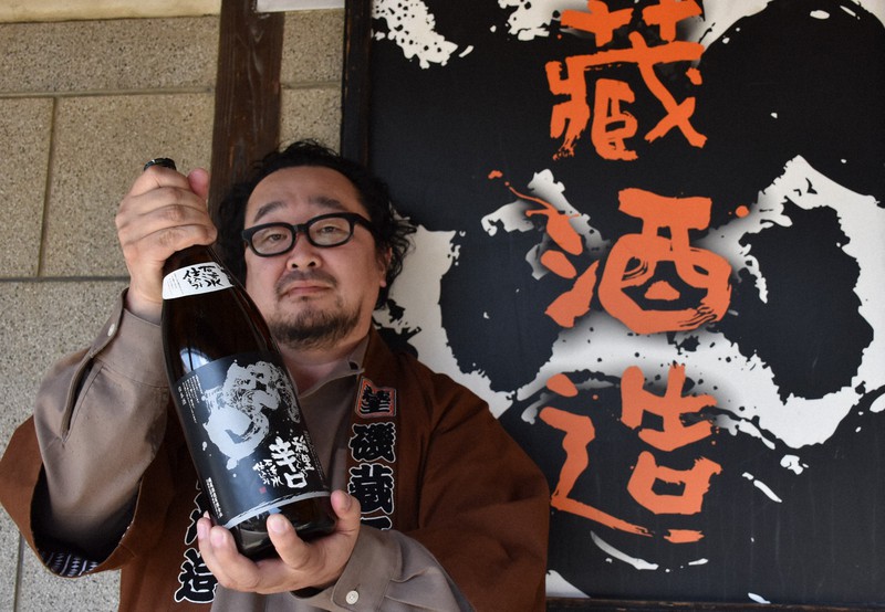 主力商品である「稲里辛口」を掲げる蔵主の磯貴太さん=茨城県笠間市の磯蔵酒造で