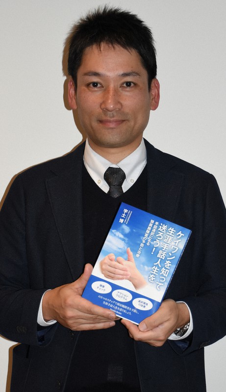 手話通訳者の職業病を紹介する本を手にする槇原章二さん=鳥取市で2020年4月8日午後7時7分、阿部絢美撮影