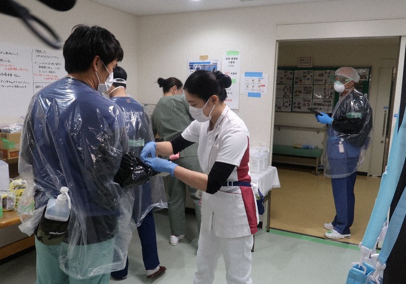 防護服の着脱場所で準備する看護師ら。不足のガウンをゴミ袋で代用し、ウイルス侵入を防ぐテープで手袋と服のすき間を目張りしている=千葉県東庄町で17日、黒田阿紗子撮影