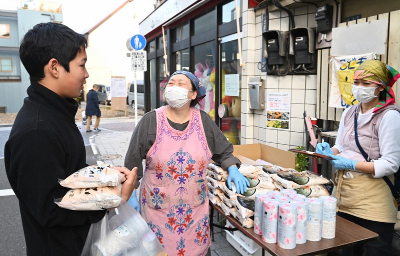 米などの食品を取りに来た中学生に声をかける薄葉聖子さん(中央)=東京都品川区で2020年4月19日午後、大西岳彦撮影