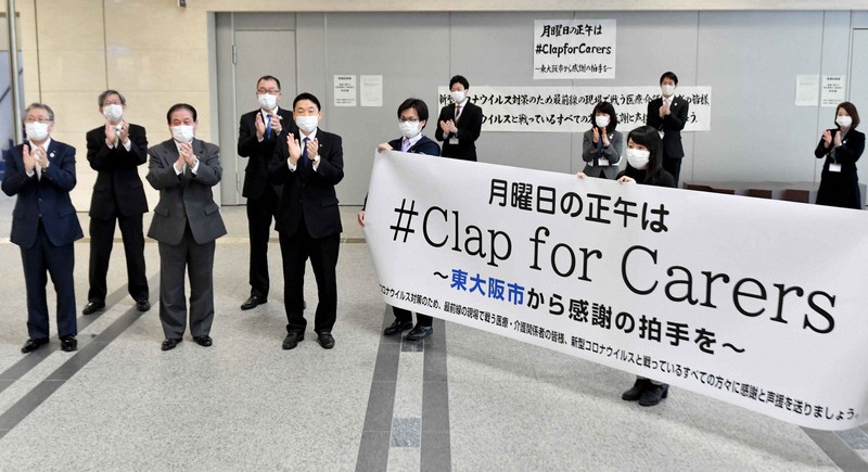 医療従事者へ拍手を送る東大阪市役所の職員たち=東大阪市で2020年4月20日午後0時3分、平川義之撮影