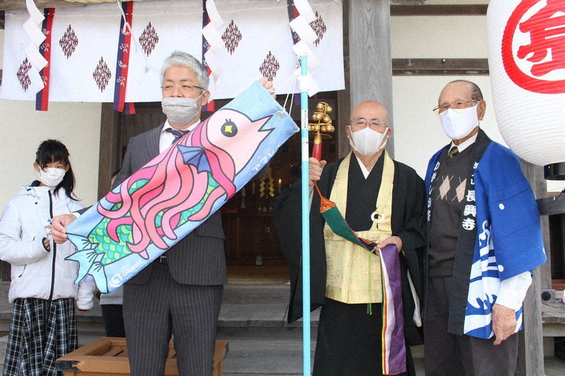 奉納したアマビエこいのぼりを手にする窪野岳社長(左から2人目)と松下宗柏住職(同3人目)=静岡県沼津市大塚の長興寺で