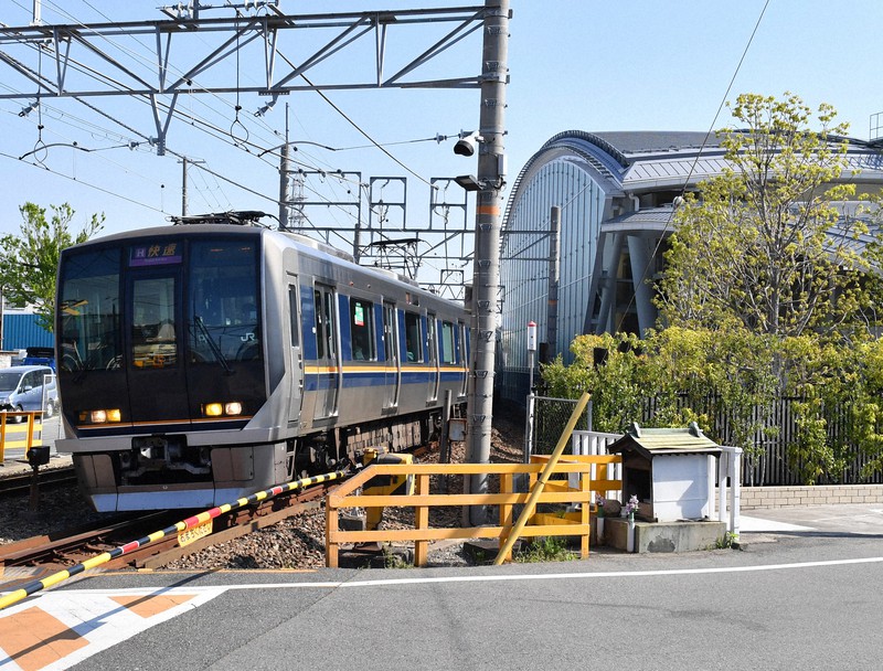 事故現場の「祈りの杜」(右)を通過する列車=兵庫県尼崎市で2020年4月25日午前8時48分、木葉健二撮影