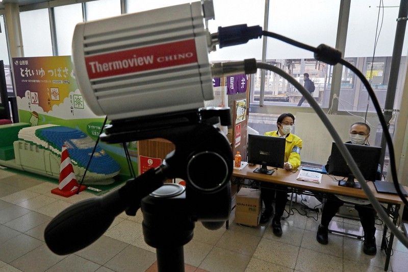 山形新幹線の改札口で、東京方面から到着する乗客の体温を測るためサーモグラフィー(手前)を設置し、モニターを見つめる県職員ら(右奥)=山形市のJR山形駅で2020年4月25日、和田大典撮影