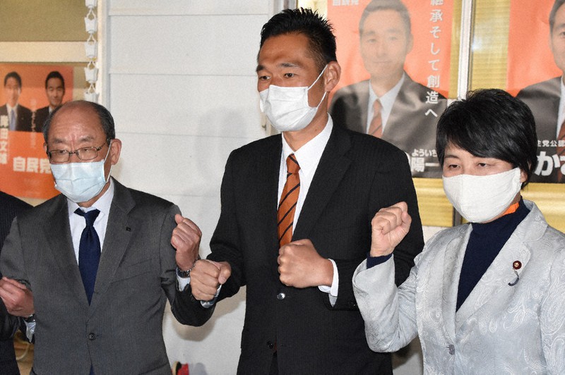 当選を確実にして自民党県連幹部らとひじを合わせる深沢陽一氏(中央)=26日午後8時15分