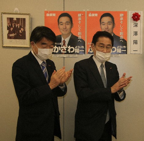 自民新人が当選確実となり、候補者名にバラを付けて拍手する岸田文雄政調会長(右)=2020年4月26日午後8時38分(代表撮影)