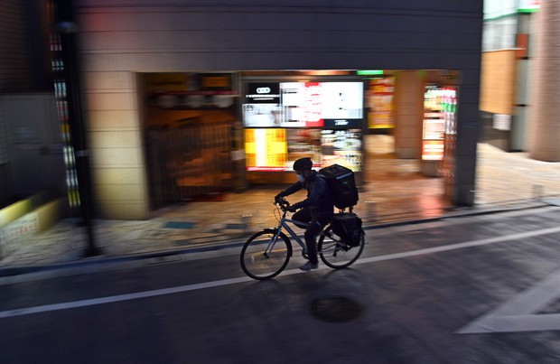 外出自粛が呼びかけられる東京都内で、飲食店から注文客の家まで料理を運ぶ配達員の男性。新型コロナウイルスの影響でデリバリーサービスの需要が高まっており、この男性も多い日で1日二十数件を請け負うという=東京都豊島区で2020年4月29日、北山夏帆撮影