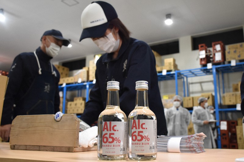 消毒に使える「南部美人アルコール65」にラベルを張る社員たち=二戸市下斗米で