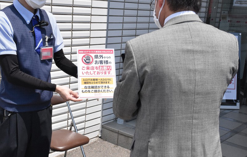 客に住所が書かれた免許証などの提示を求めるパチンコ店の従業員(左)=徳島県鳴門市で2020年5月2日午前11時38分、松山文音撮影(画像の一部を加工しています)