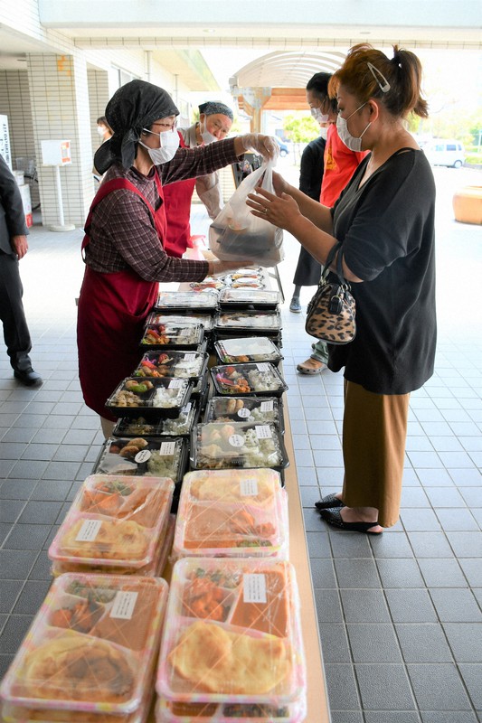店の個性あふれるおかずが盛りだくさんの「もりやま元気べんとう」を受け取る市民=守山市下之郷3のすこやかセンターで2020年5月1日、礒野健一撮影