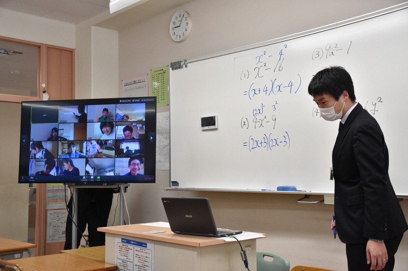 一斉休校を受け、インターネットを介した遠隔授業の実験に取り組む田中信行教諭と、モニター(左)に映し出された自宅の生徒たち=岩美町立岩美中で、阿部絢美撮影