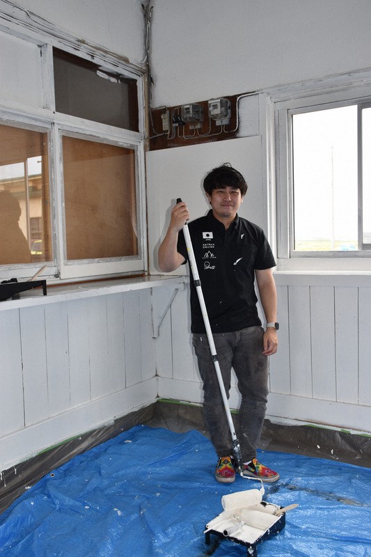 アート製作の準備のため壁に白いペンキを塗るGOMAさん=青森県田舎館村高樋の田舎館駅で2020年5月4日午後1時6分、江沢雄志撮影