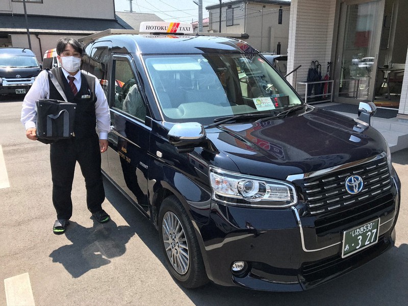 フロントガラスに「おつかいタクシー」と掲げたタクシー。運転手は買い物用のバッグを持っている=報徳タクシー提供