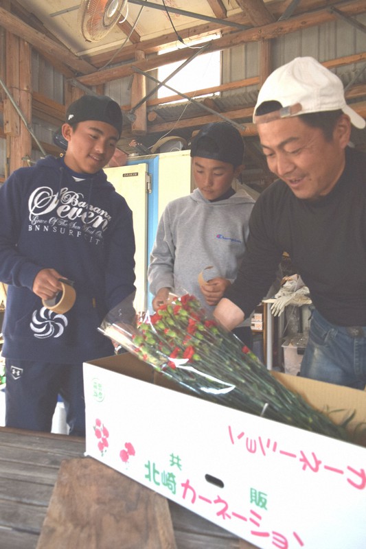 母の日を前にカーネーションの出荷作業に追われる楢崎さん(右)と長男の賢翔さん(左)、次男の太翔さん