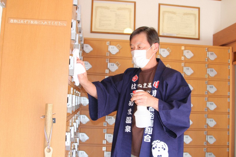 除菌スプレーを吹きかけた雑巾でげた箱を丁寧にぬぐう近藤和幸さん=東京都大田区西蒲田6の「はすぬま温泉」で2020年5月8日午後2時8分、生野由佳撮影