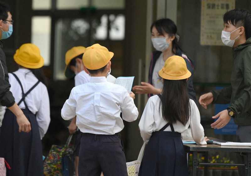 休校期間中の体調を記した健康観察表を提出して、教室に向かう児童たち=大阪市西区の市立九条東小で2020年5月11日午前8時11分、久保玲撮影