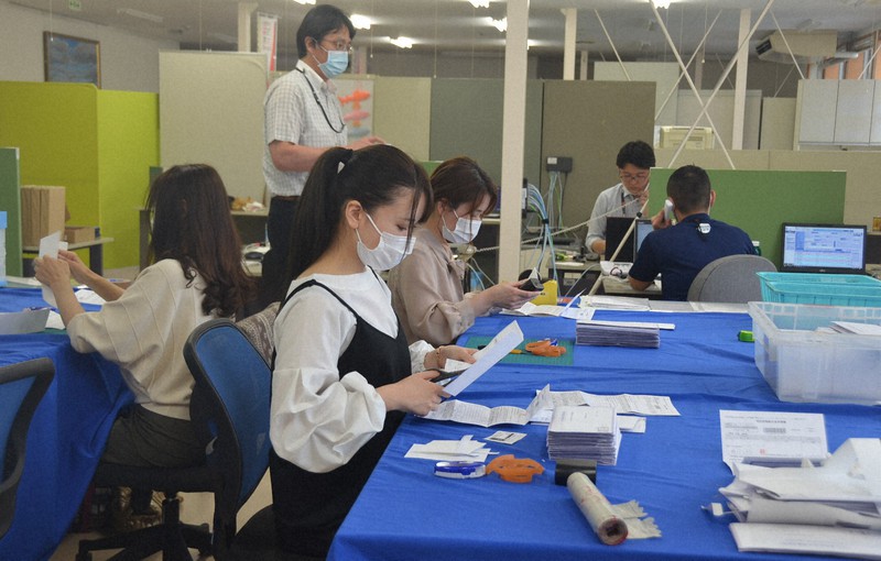 郵送された申請書を1枚ずつチェックする職員ら=栃木県大田原市役所で2020年5月18日午後3時19分、湯浅聖一撮影
