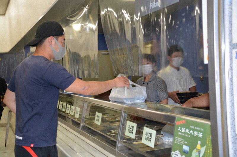 久留米大で「100円夕食弁当」を購入する学生(左)=福岡県久留米市で、高芝菜穂子撮影