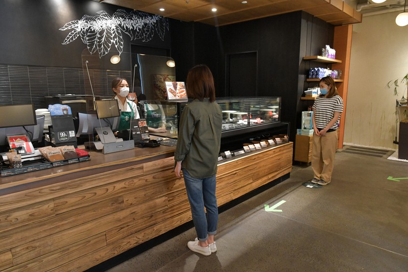 スターバックスコーヒージャパンは営業再開にあたりレジ前で客同士の距離を保つなど新型コロナウイルス対策を講じている=同社提供
