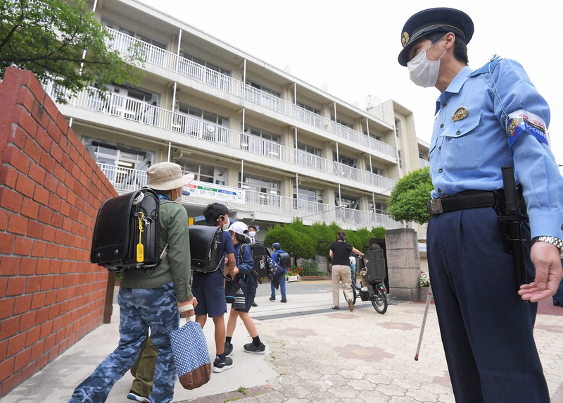 校門前で児童の登校を見守る警察官=福岡市中央区で2020年5月21日午前7時55分、津村豊和撮影