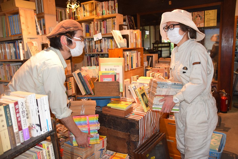 休業中に本の整理をしている中田茂美さん(右)と俊昭さん=三重県名張市中町で2020年5月15日午後2時38分