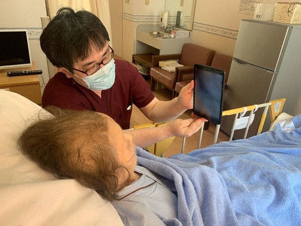 広橋医師が手にしたタブレット端末を通して家族と面会する患者=広橋医師提供