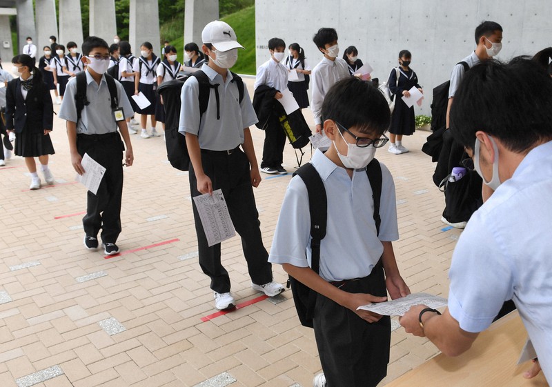 間隔を空けて健康チェックカードを提出する生徒たち=愛知県瀬戸市の市立にじの丘学園で2020年5月25日午前7時58分、兵藤公治撮影