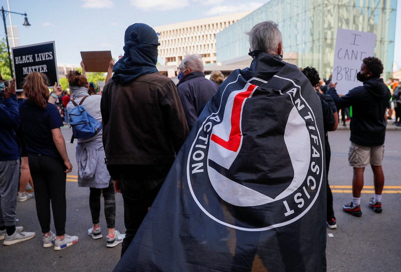 極左集団「アンティファ」の旗を身にまとう抗議デモ参加者=米東部マサチューセッツ州ボストンで2020年5月31日、ロイター